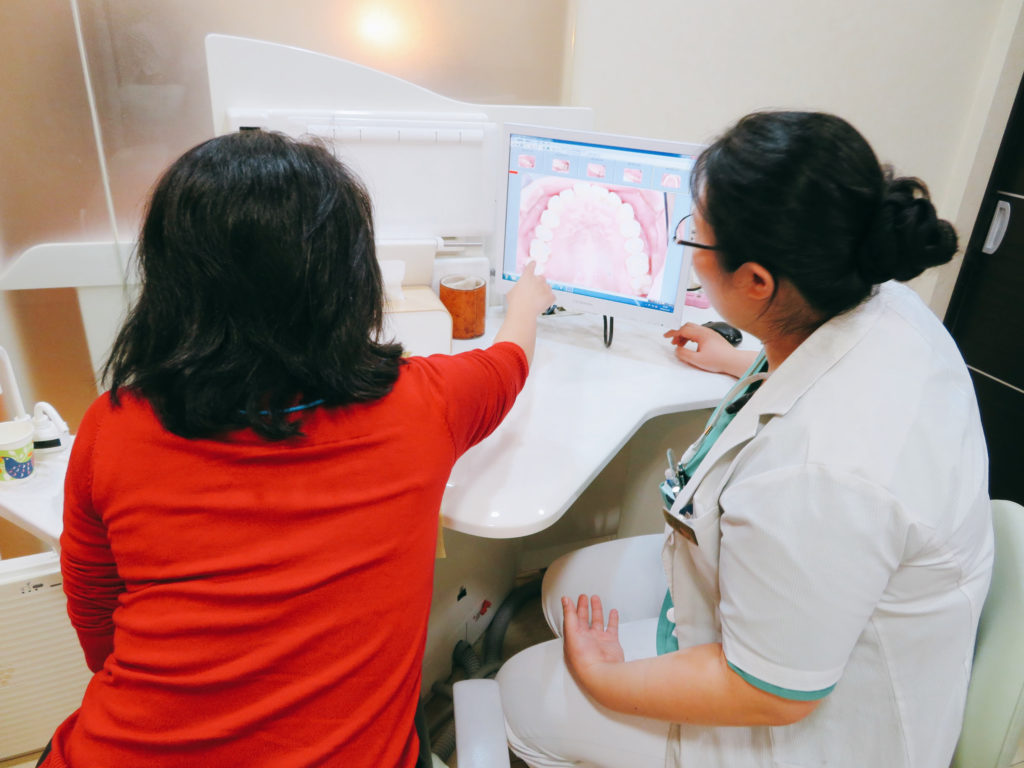 モニターで口腔内の状態を見ながら説明を受けている場面